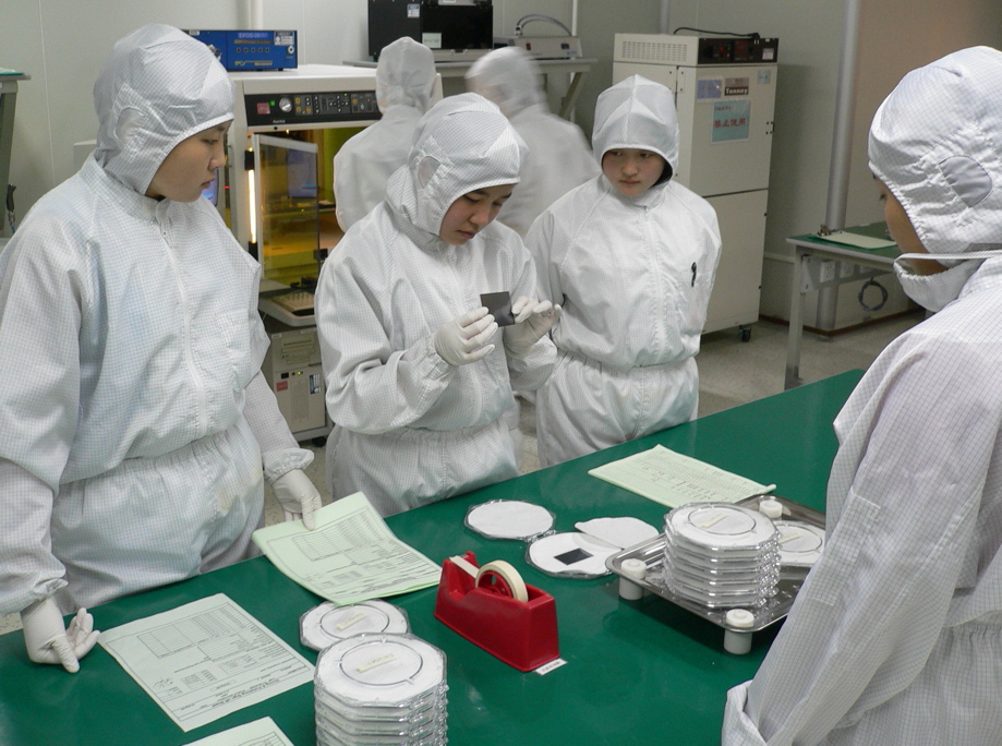 Engineers inspecting equipment inside a semiconductor cleanroom